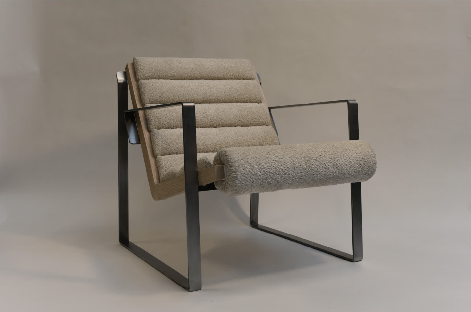 RØN chair, three-quarter view showing steel frame and bouclé cushions